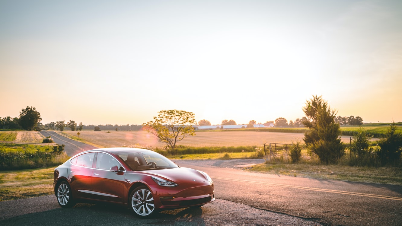Tesla ev car in front of field
